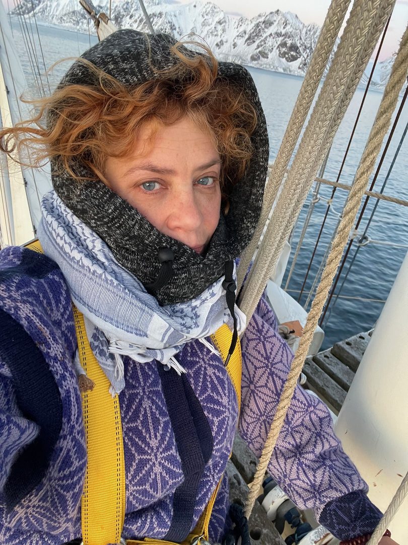 a woman wearing a scarf and a hat on a boat